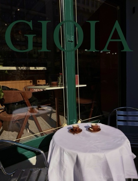 Das Schaufenster mit dem Schriftzug GIOIA, davor ein weiß gedeckter Terrassentisch mit zwei Espressotassen.