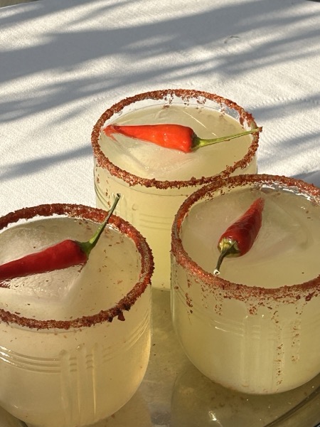 Drei Spicy Margaritas mit Salzrand und je einer roten Chilischote im Glas.