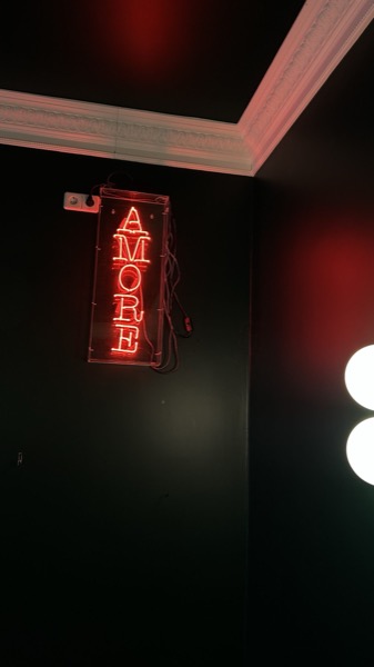Die rote Neonschrift AMORE an der dunkelgrünen Wand des Gastraums.