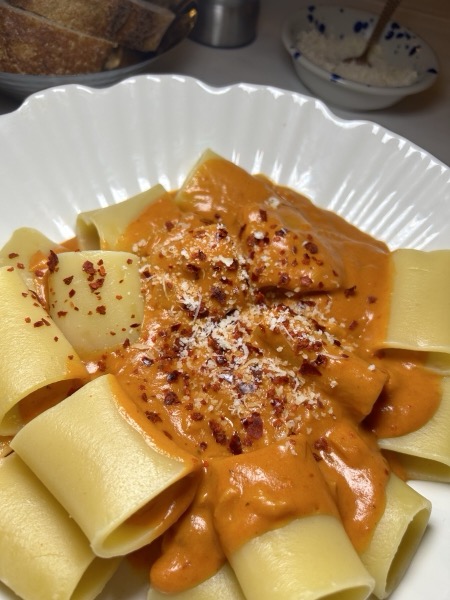 Paccheri alla Vodka mit cremiger Tomatensauce auf einem weißen Wellenteller.