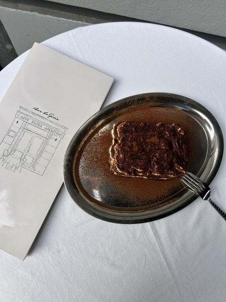 Hausgemachtes Tiramisù auf einem Silberteller neben einer Serviette.